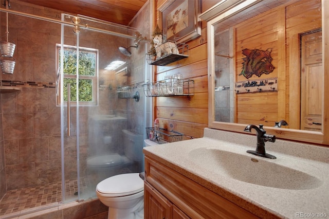 bathroom with wooden walls, a shower stall, toilet, and vanity