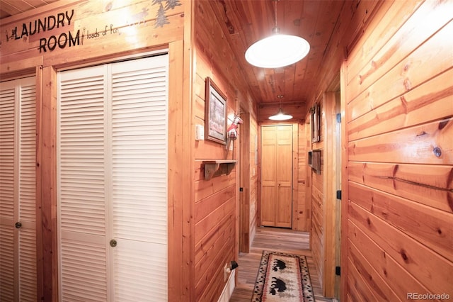 hall featuring wooden walls, light wood-style floors, and wood ceiling