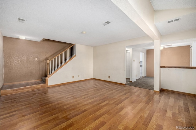 unfurnished living room featuring hardwood / wood-style flooring and a textured ceiling