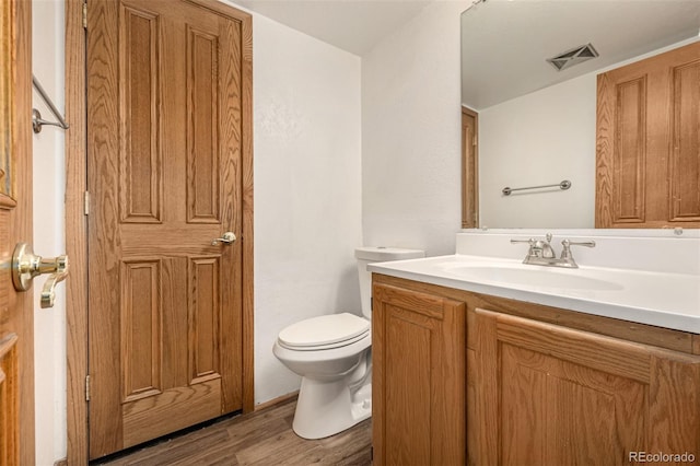 bathroom with hardwood / wood-style floors, vanity, and toilet