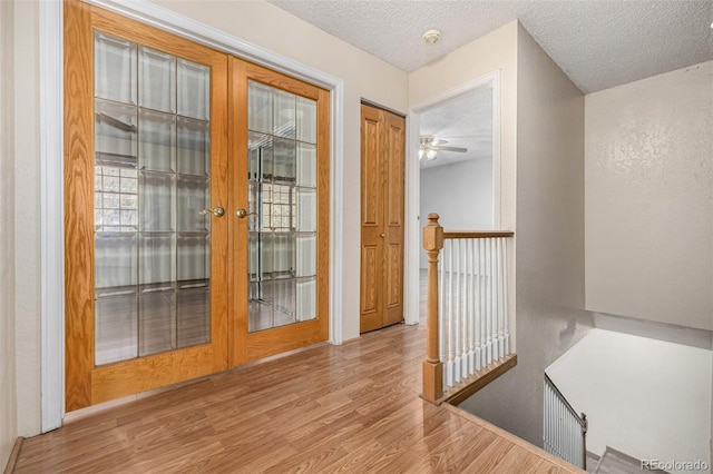 entryway with french doors, a textured ceiling, light wood-type flooring, and ceiling fan