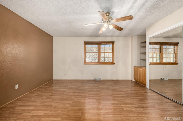 unfurnished living room featuring light hardwood / wood-style floors, ceiling fan, and a textured ceiling