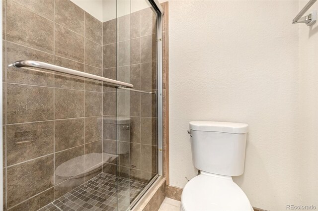 bathroom featuring toilet and a shower with door