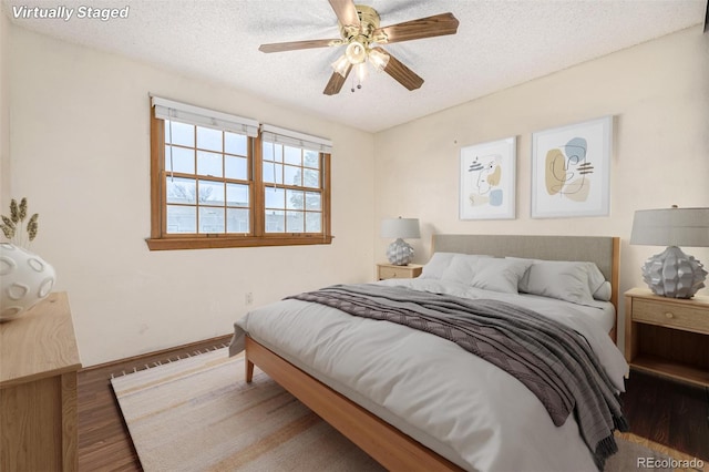 bedroom with a textured ceiling, ceiling fan, and dark wood-type flooring