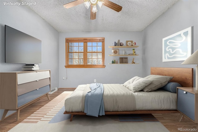 bedroom with ceiling fan, light wood-type flooring, and a textured ceiling