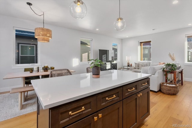 kitchen featuring dark brown cabinets, a center island, light hardwood / wood-style flooring, and hanging light fixtures