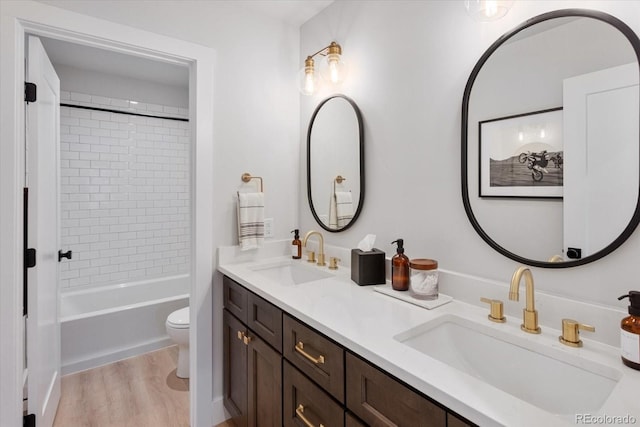 full bathroom featuring hardwood / wood-style floors, vanity, toilet, and tiled shower / bath combo