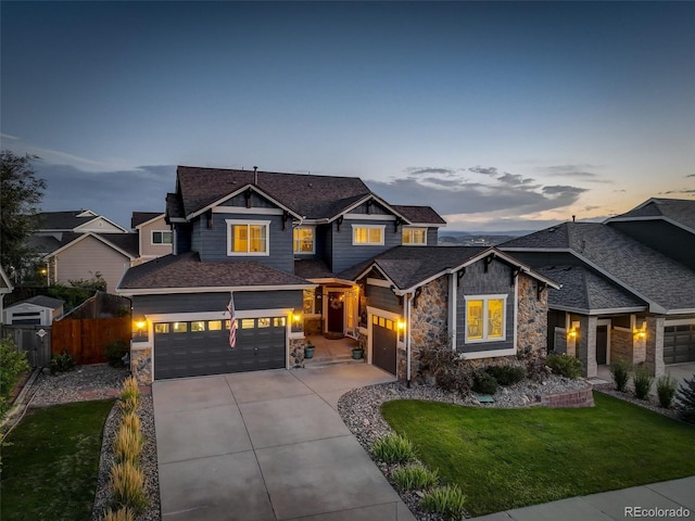 craftsman house with a front yard, fence, driveway, and stone siding