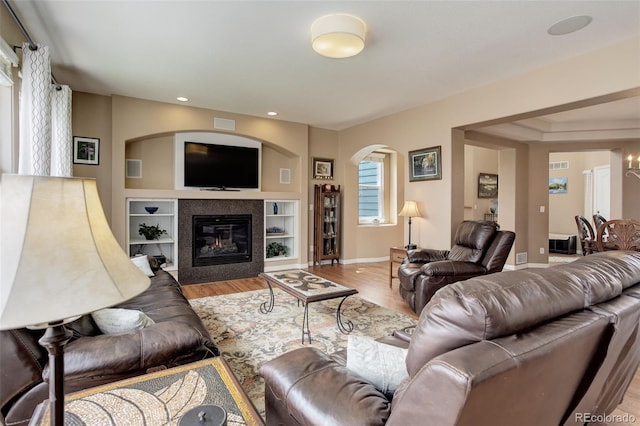 living area featuring arched walkways, a fireplace, wood finished floors, baseboards, and recessed lighting