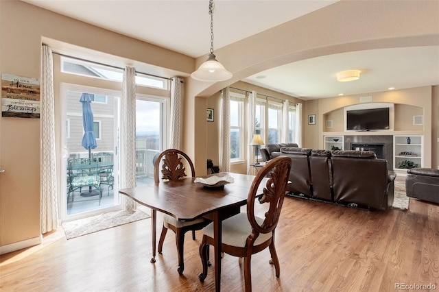 dining space with a tiled fireplace and light wood-type flooring