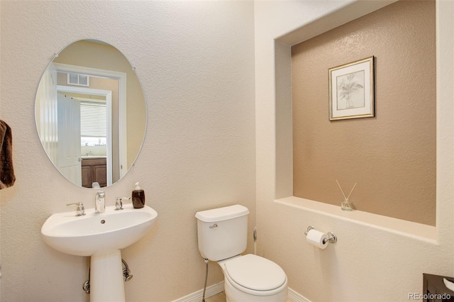 half bathroom featuring toilet, visible vents, and a sink