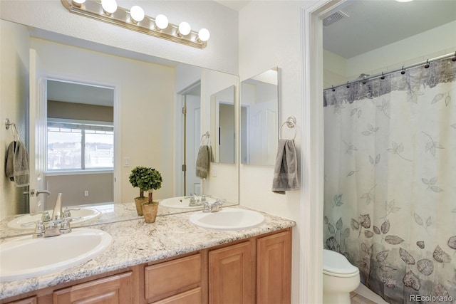 full bathroom featuring a sink, toilet, double vanity, and visible vents