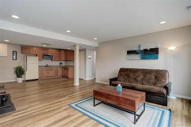 living room featuring recessed lighting, baseboards, visible vents, and light wood-style flooring