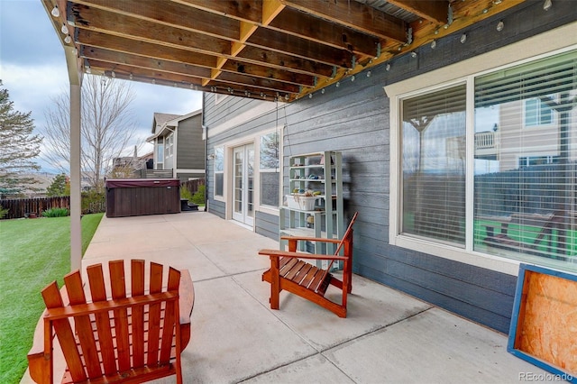 view of patio / terrace with a hot tub and fence