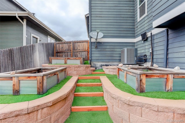 view of yard featuring fence, cooling unit, and a vegetable garden