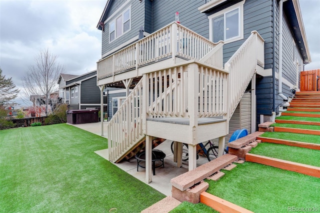 rear view of house with a deck, stairs, a patio area, a lawn, and a hot tub