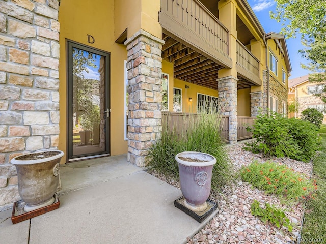 9896 W Freiburg Dr Unit 1D, Littleton, CO 80127 - view of exterior entry with stone siding, stucco siding, and a balcony