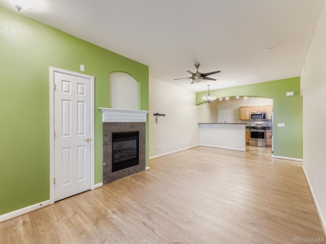 9896 W Freiburg Dr Unit 1D, Littleton, CO 80127 - unfurnished living room with a tile fireplace, light wood-style flooring, ceiling fan, and a chandelier
