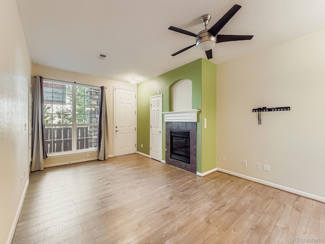 9896 W Freiburg Dr Unit 1D, Littleton, CO 80127 - unfurnished living room with wood finished floors, a tile fireplace, and a ceiling fan