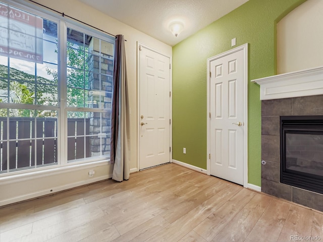 9896 W Freiburg Dr Unit 1D, Littleton, CO 80127 - unfurnished living room with light wood finished floors, a textured wall, and a tiled fireplace