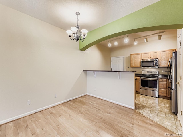 9896 W Freiburg Dr Unit 1D, Littleton, CO 80127 - kitchen featuring stainless steel appliances, dark countertops, a chandelier, a peninsula, and arched walkways