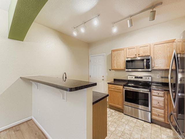 9896 W Freiburg Dr Unit 1D, Littleton, CO 80127 - kitchen with appliances with stainless steel finishes, a peninsula, dark countertops, and a breakfast bar area