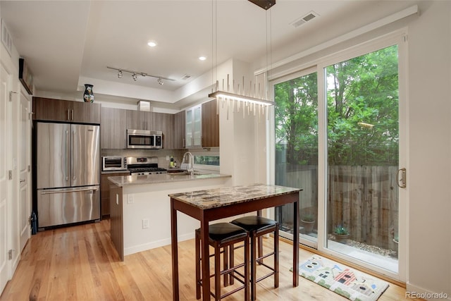 2138 N Glenarm Pl, Denver, CO 80205 - kitchen featuring stainless steel appliances, a peninsula, a sink, and light wood-type flooring