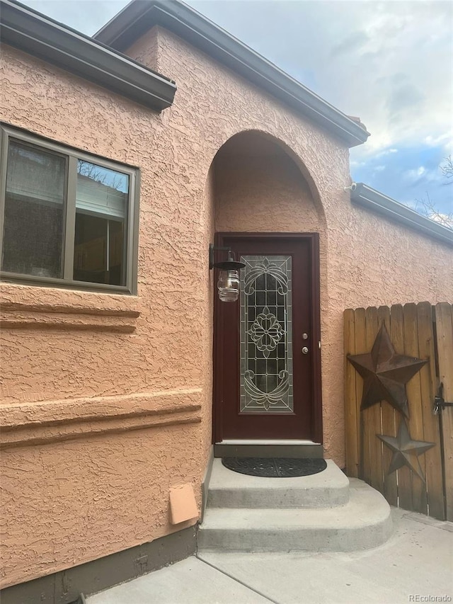 property entrance with fence and stucco siding