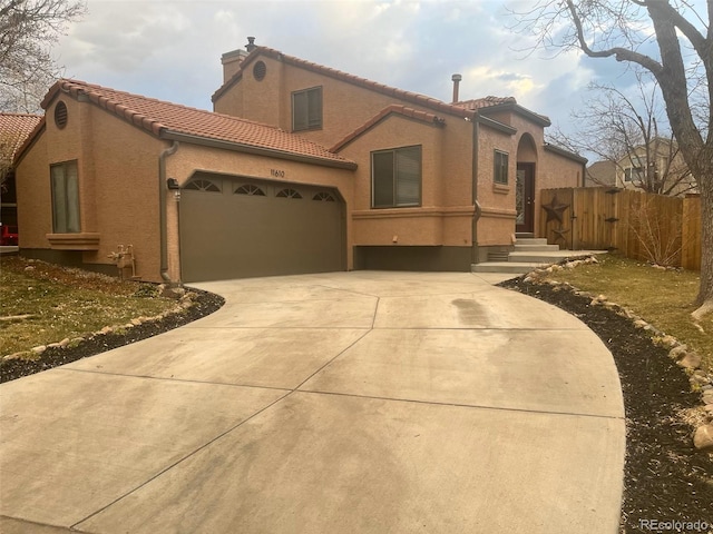 mediterranean / spanish-style home with fence, driveway, an attached garage, stucco siding, and a tiled roof