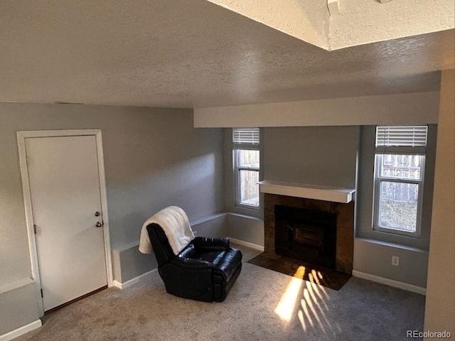 sitting room with carpet flooring, a fireplace, baseboards, and a textured ceiling