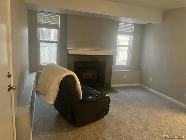 carpeted living area with a fireplace and baseboards