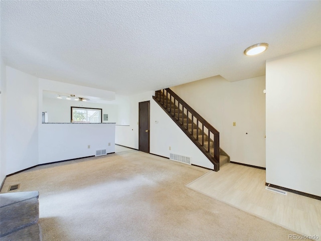 unfurnished living room featuring a textured ceiling and light colored carpet