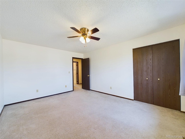 unfurnished bedroom featuring a textured ceiling, light colored carpet, ceiling fan, and a closet