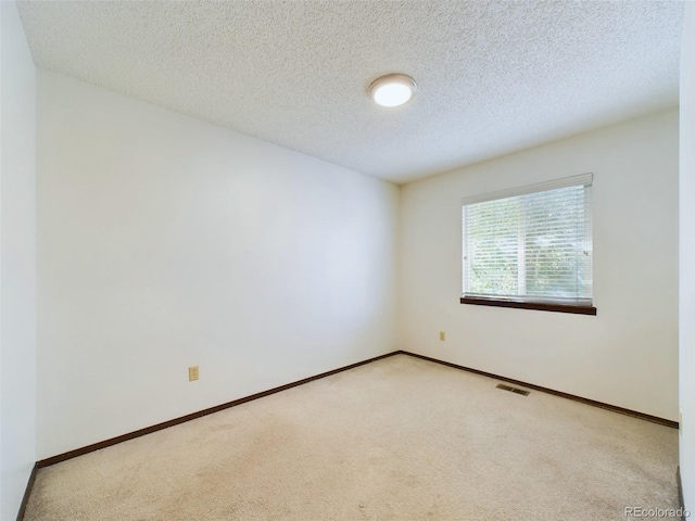 unfurnished room featuring light colored carpet and a textured ceiling