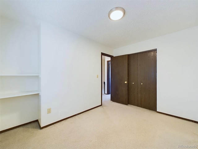 unfurnished bedroom with a textured ceiling, light colored carpet, and a closet