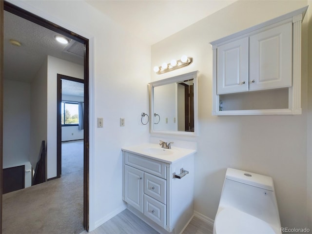 bathroom featuring toilet, a textured ceiling, and vanity