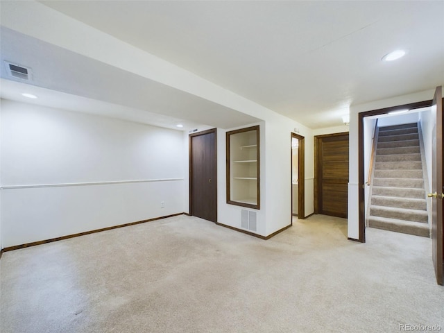 basement featuring built in shelves and light colored carpet