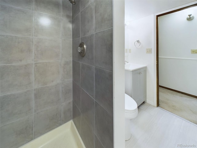 bathroom featuring tiled shower, vanity, and toilet