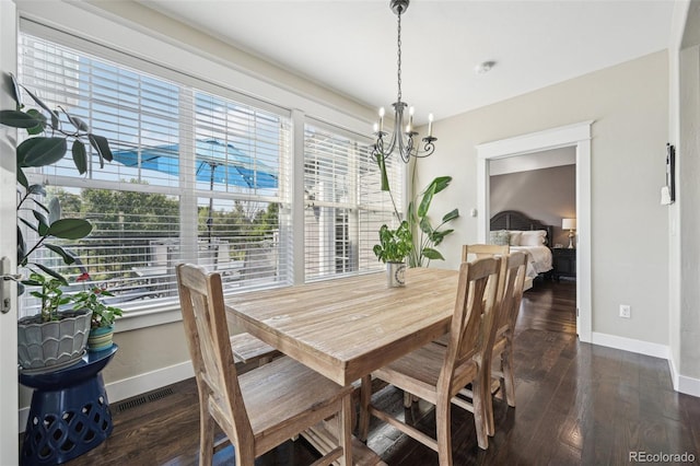 dining area with dark hardwood / wood-style flooring and an inviting chandelier