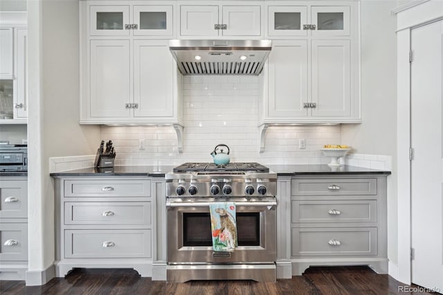 kitchen with backsplash, white cabinets, high end stainless steel range, and wall chimney exhaust hood