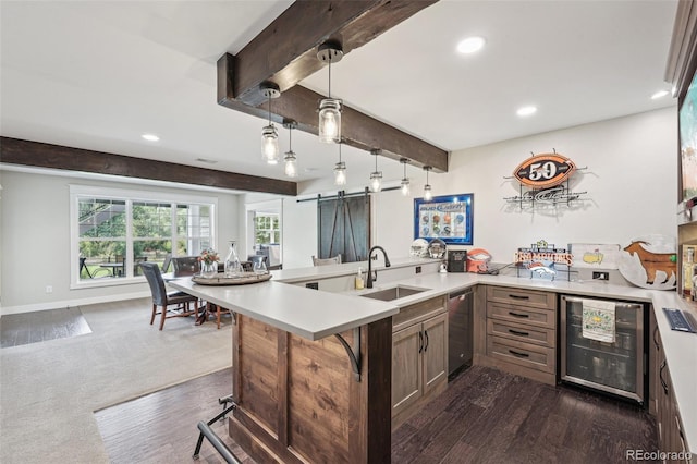 kitchen with sink, hanging light fixtures, a kitchen breakfast bar, a barn door, and beamed ceiling