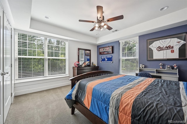 carpeted bedroom featuring a tray ceiling and ceiling fan