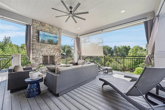 sunroom with an outdoor stone fireplace and ceiling fan