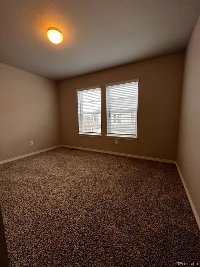 empty room featuring carpet flooring and baseboards