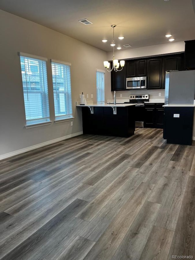 kitchen with visible vents, dark cabinetry, an inviting chandelier, stainless steel appliances, and a sink