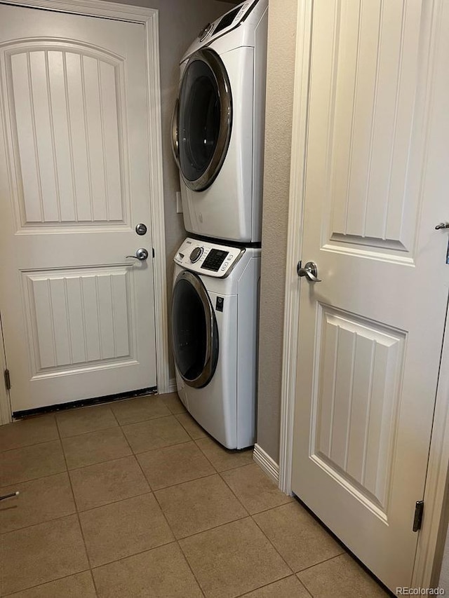 washroom with light tile patterned floors, laundry area, and stacked washer / dryer