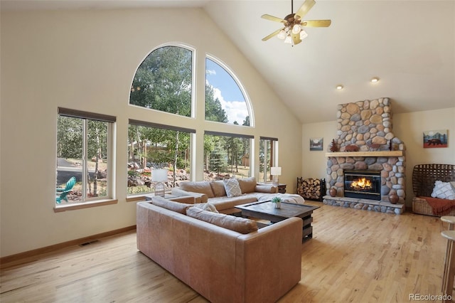 living room with ceiling fan, high vaulted ceiling, a fireplace, and light hardwood / wood-style flooring