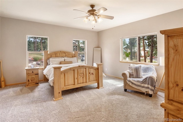 bedroom with ceiling fan, light carpet, and multiple windows