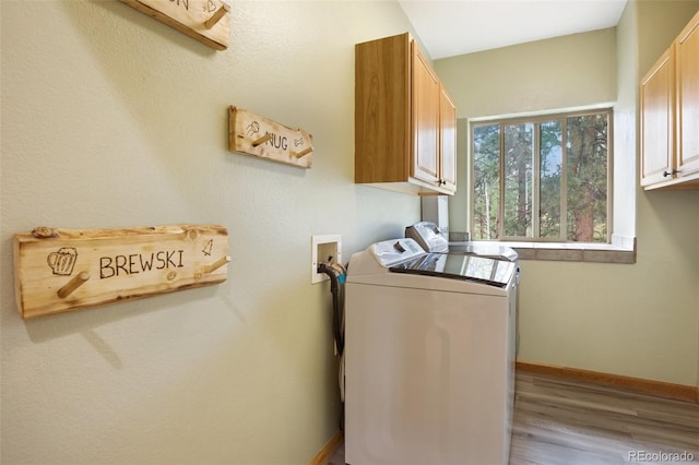 laundry room with cabinets, washer and clothes dryer, and light hardwood / wood-style flooring