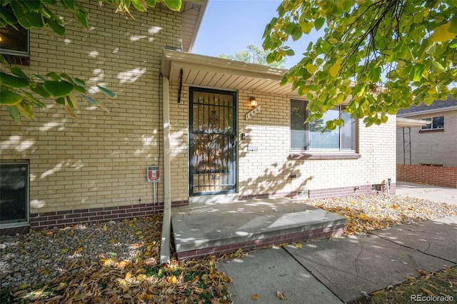 property entrance featuring crawl space and brick siding
